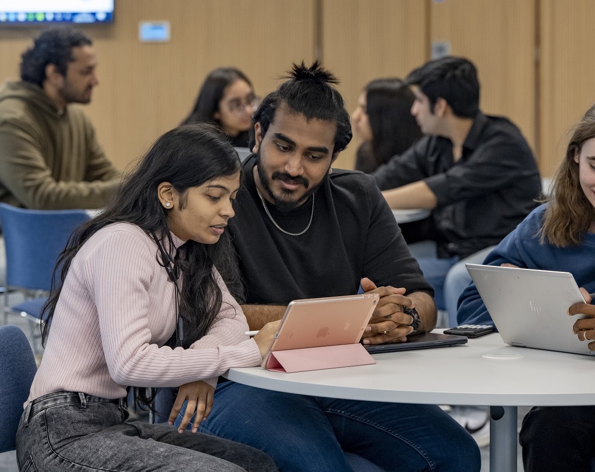 Students work and relax at tables in a communal space