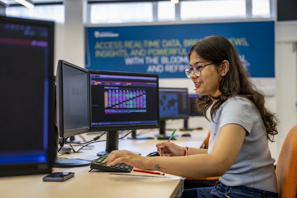 Female student working at a keyboard with multiple screens