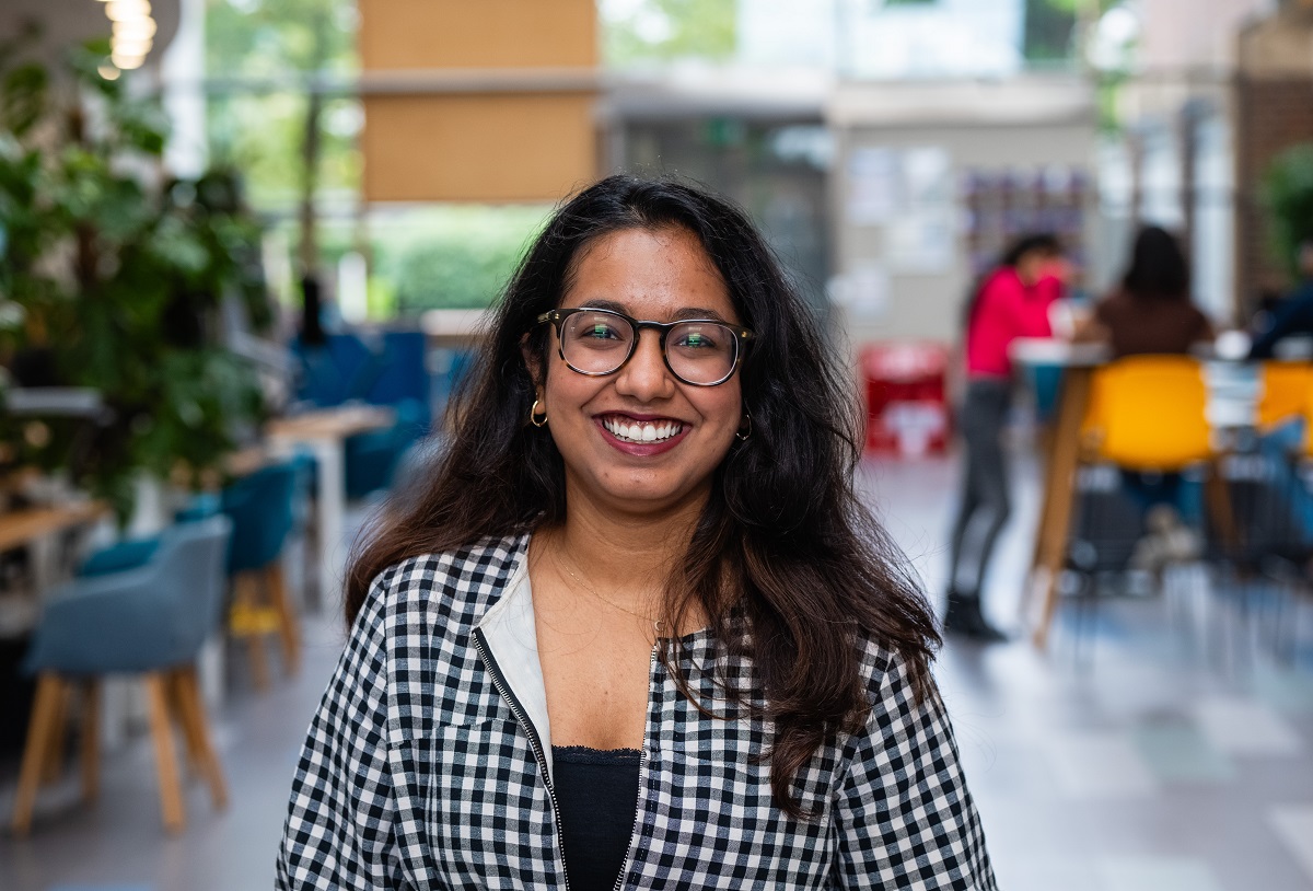 A smiling student in a professional top smiles and looks toward the camera