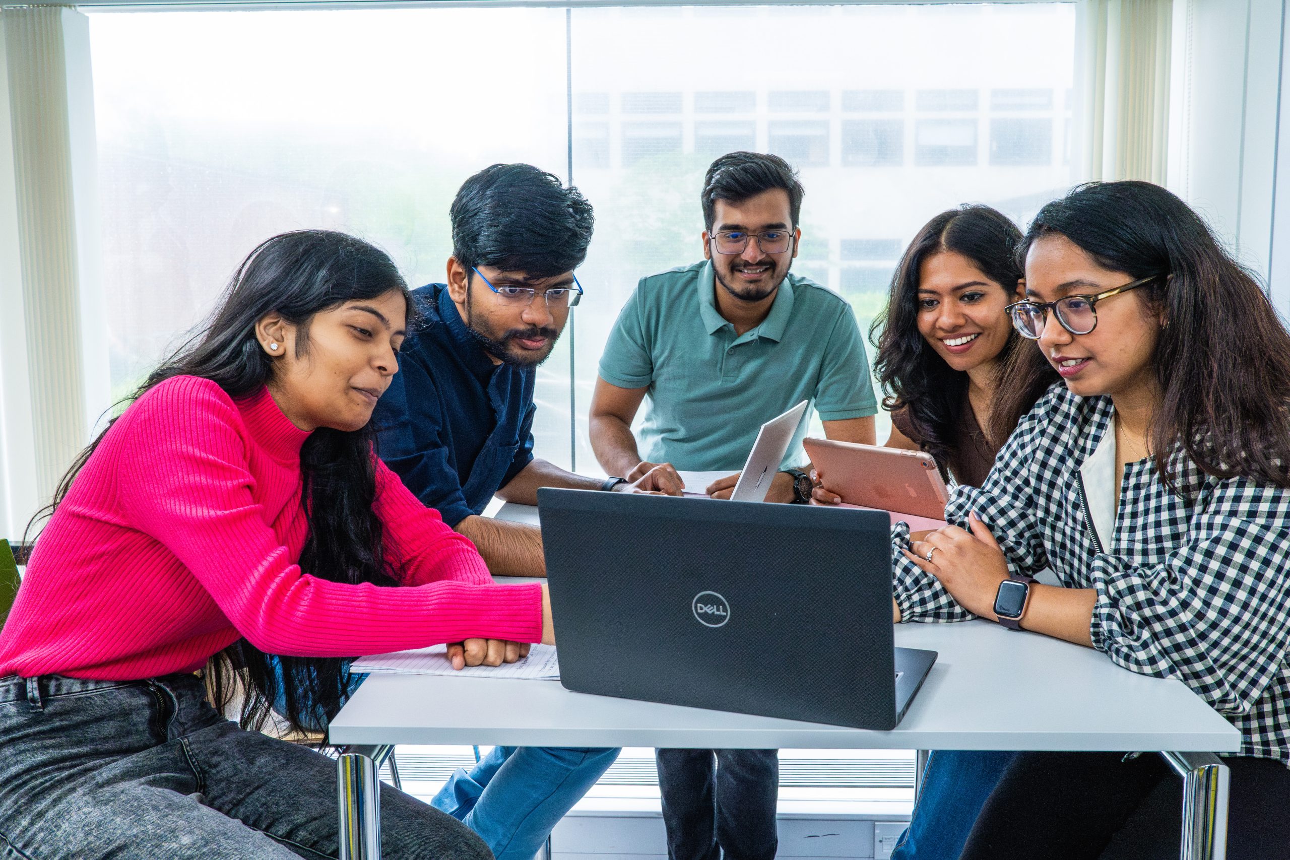 A mixed group of students looking keenly at a laptop around a table