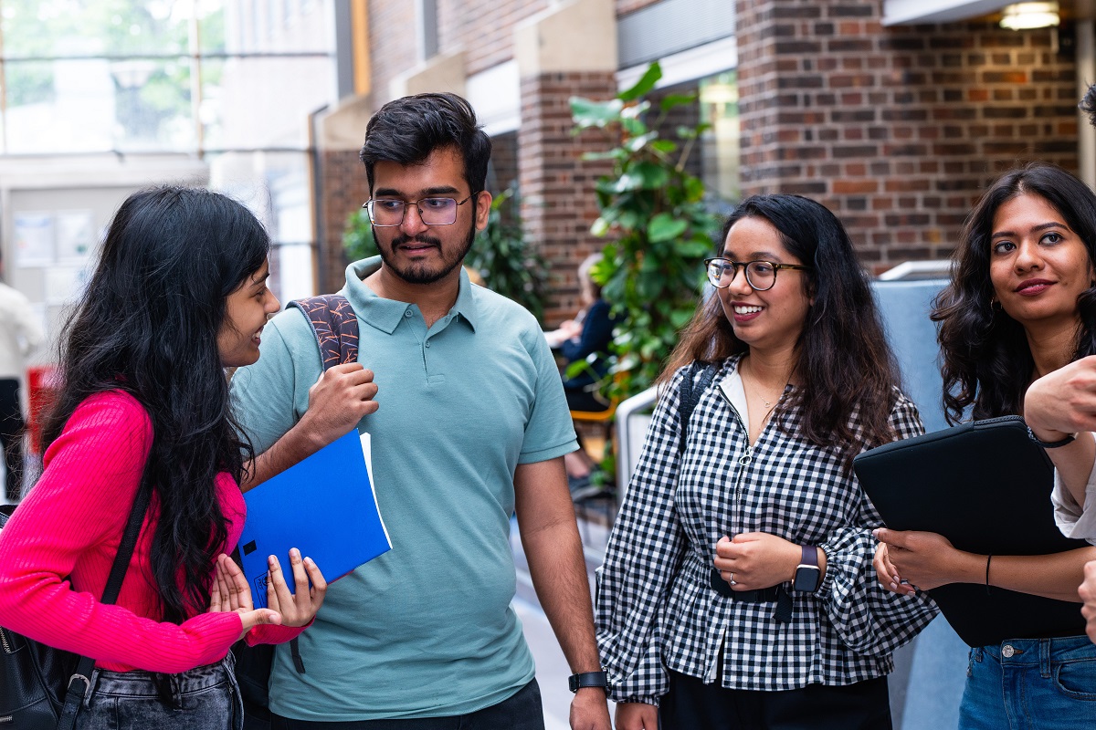 A mixed group of students gather in a university lobby on their way to a lecture